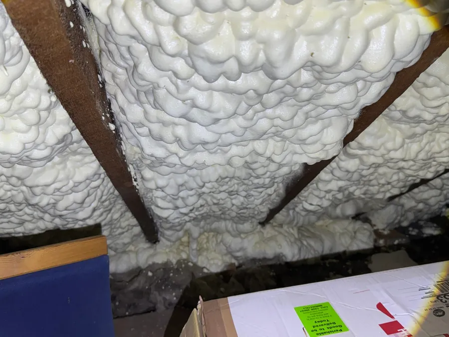 Independent spray foam loft inspection — thick open-cell spray foam sprayed between rafters on the underside of a pitched roof